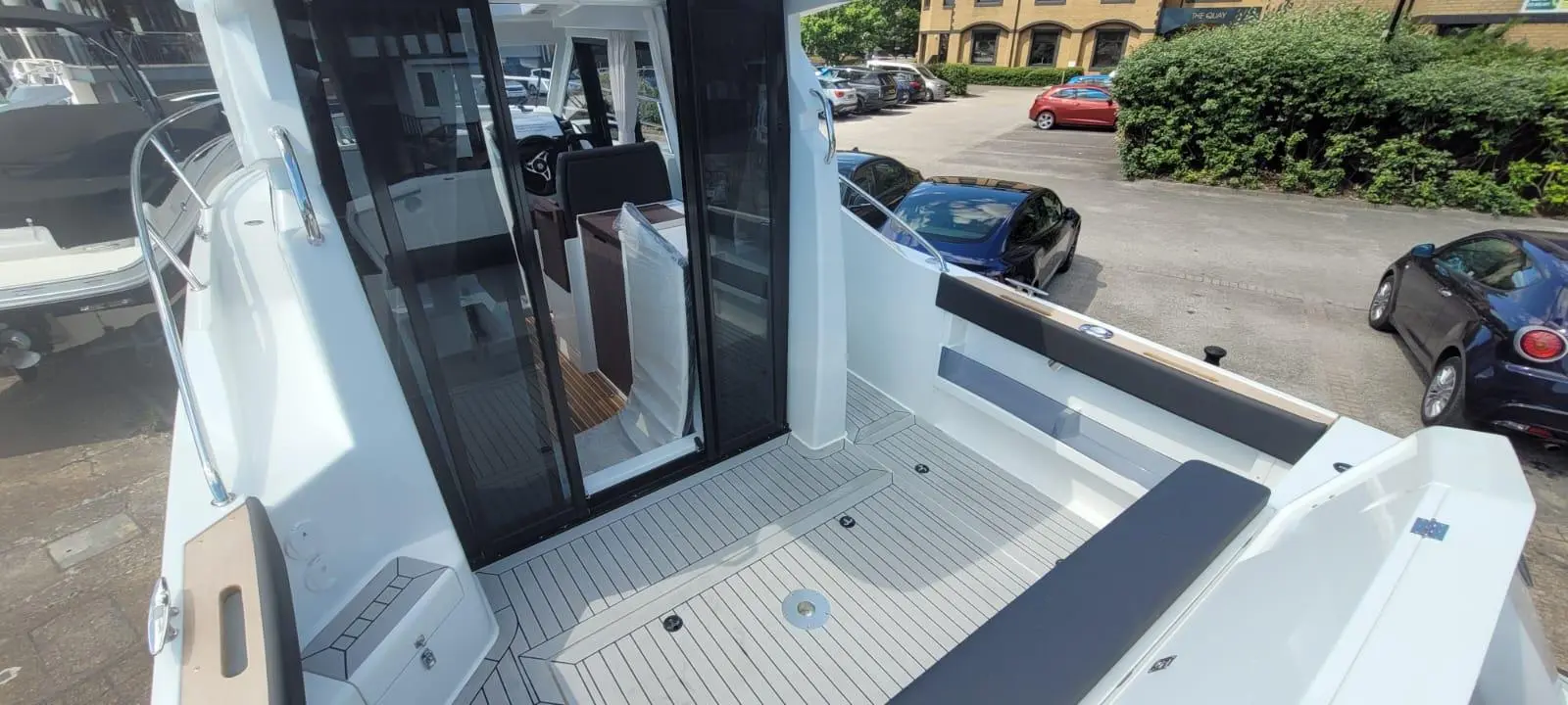 View from above of a modern boat's deck, featuring a seating area, sleek flooring, and an entrance to the cabin.